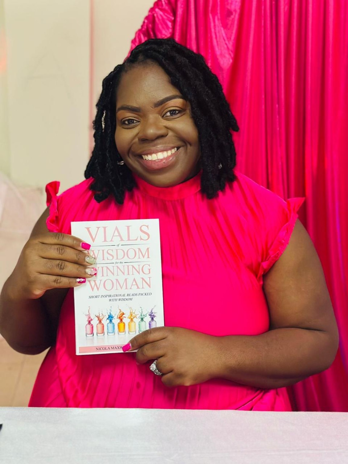 Nicola Maxwell-Johnson holding her book Vials of Wisdom for the Winning Woman